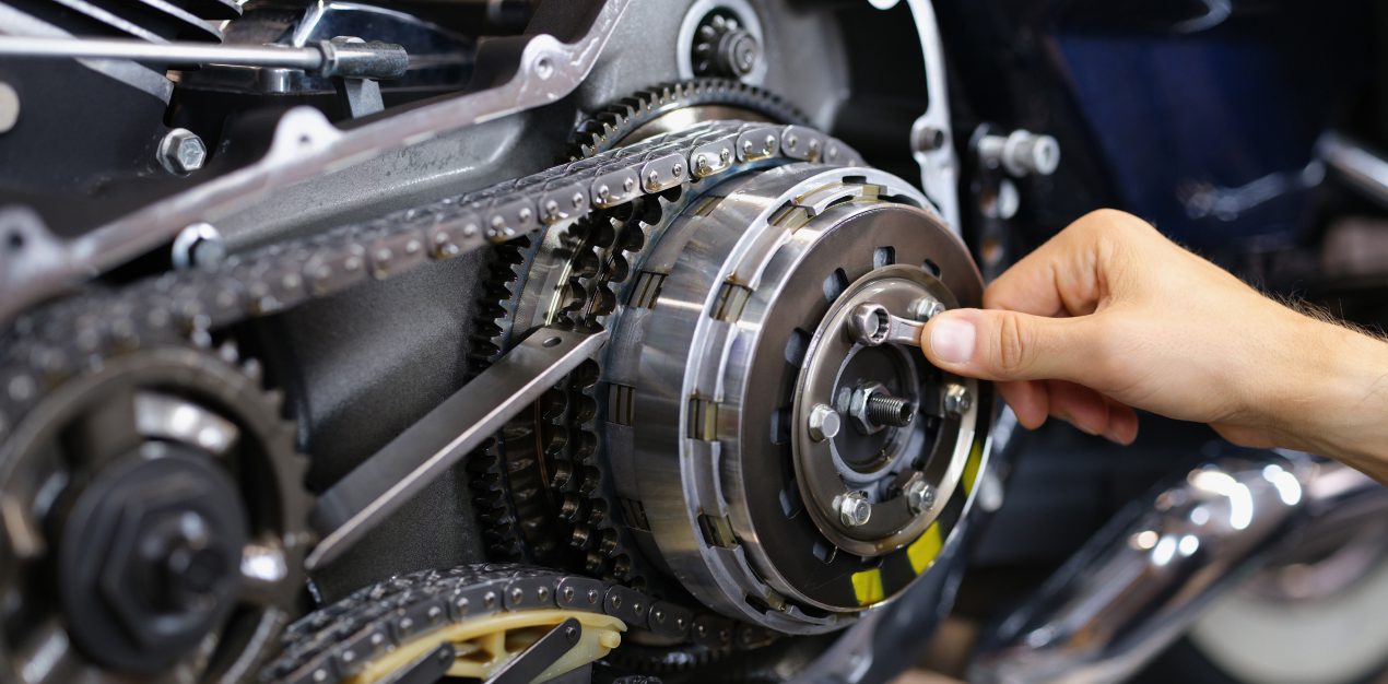 Mano ajustando el sistema de cadena y embrague de una motocicleta durante mantenimiento técnico
