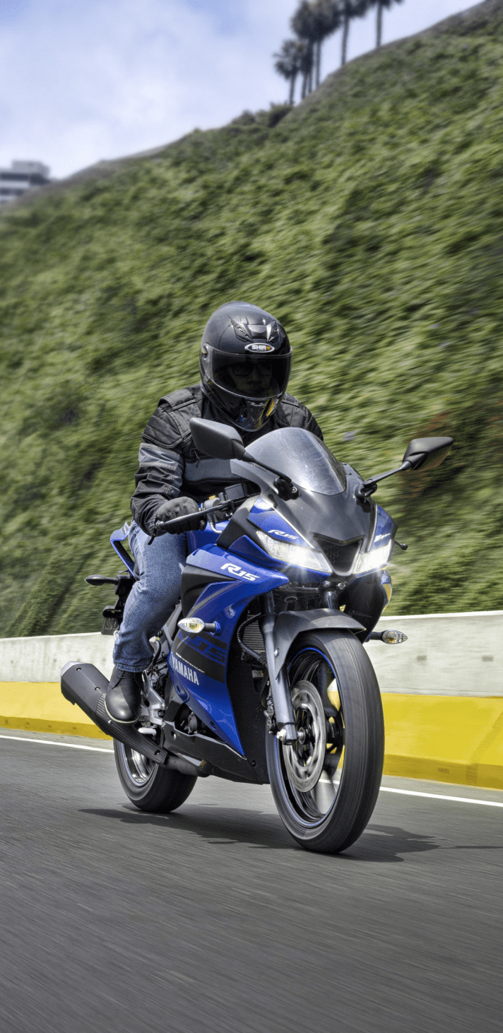 Piloto en una Yamaha YZF-R15 ABS azul en carretera, moto deportiva diseñada para velocidad y manejo ágil en ciudad y autopista