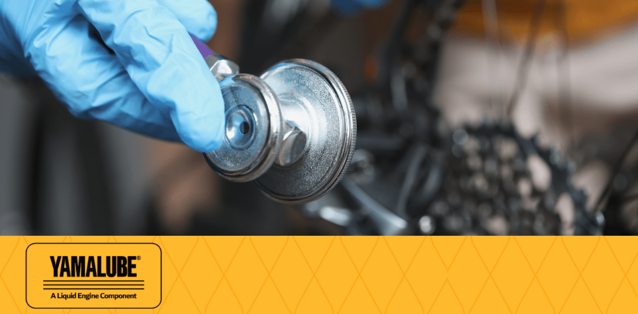 Revisión de motor de motocicleta utilizando un estetoscopio mecánico como figura ilustrativa en Kasei Motors, destacando la importancia del mantenimiento preventivo con productos como Aceite Yamalube